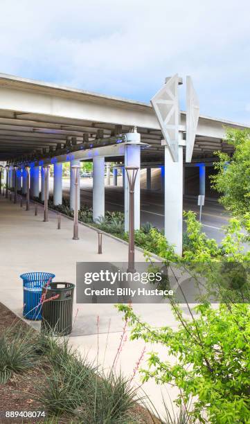 a green-leaf landscaped setting under a concrete highway overpass with garbage and recycling bins - greenleaf stock pictures, royalty-free photos & images