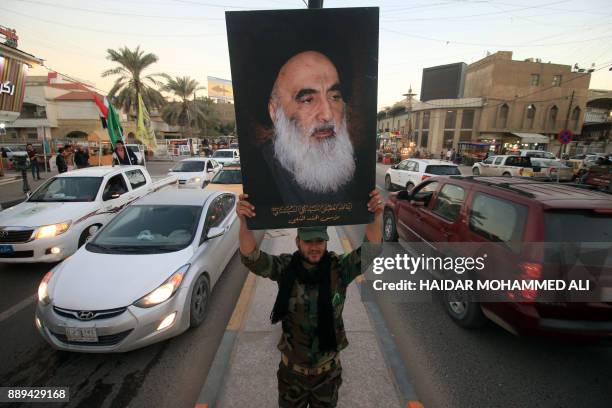 Member of the Hashed al-Shaabi carries a portrait of Iraqi Shiite cleric Grand Ayatollah Ali al-Sistani in a street in the southern city of Basra on...