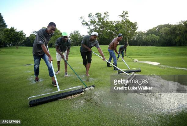 Ground keepers remove water from the 9th hole during the forth day of the Joburg Open at Randpark Golf Club on December 10, 2017 in Johannesburg,...