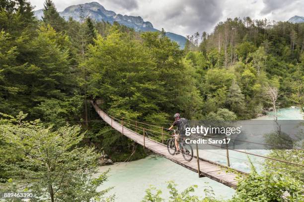 männliche mountainbiker ist die überquerung einer hängebrücke in slowenien. - glen stock-fotos und bilder