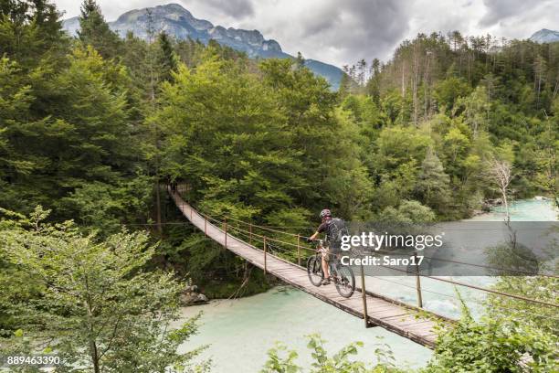 mountainbiker hombre está cruzando un puente colgante en eslovenia. - eslovenia fotografías e imágenes de stock
