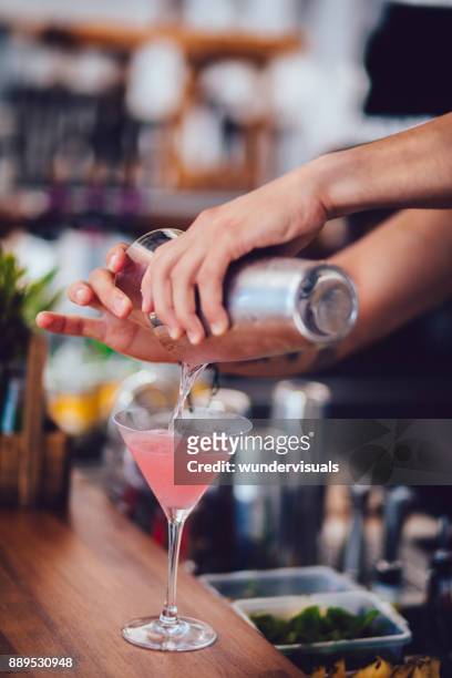 young bartender pouring cocktail in glass at summer bar - cocktail making stock pictures, royalty-free photos & images