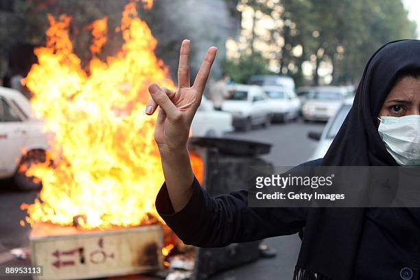 Woman protestor makes a V sign while standing in front of burning rubbish on July 9, 2009 in Tehran, Iran. Following recent unrest in the wake of the...