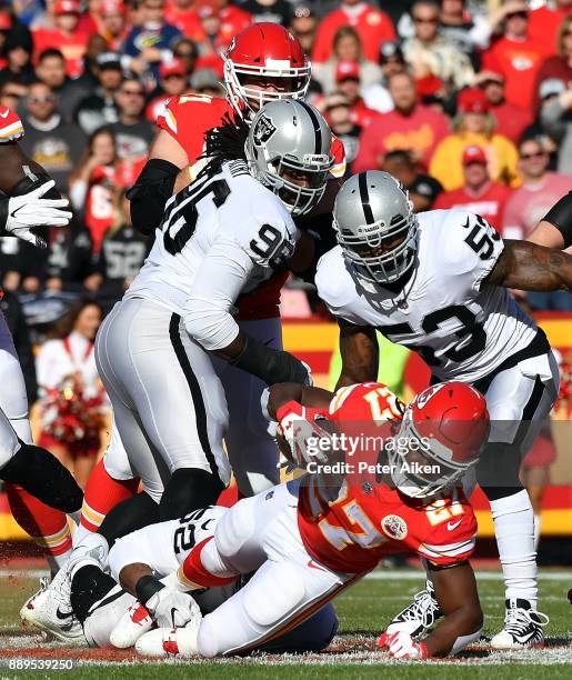 Running back Kareem Hunt of the Kansas City Chiefs carries the ball as defensive end Denico Autry and middle linebacker NaVorro Bowman of the Oakland...