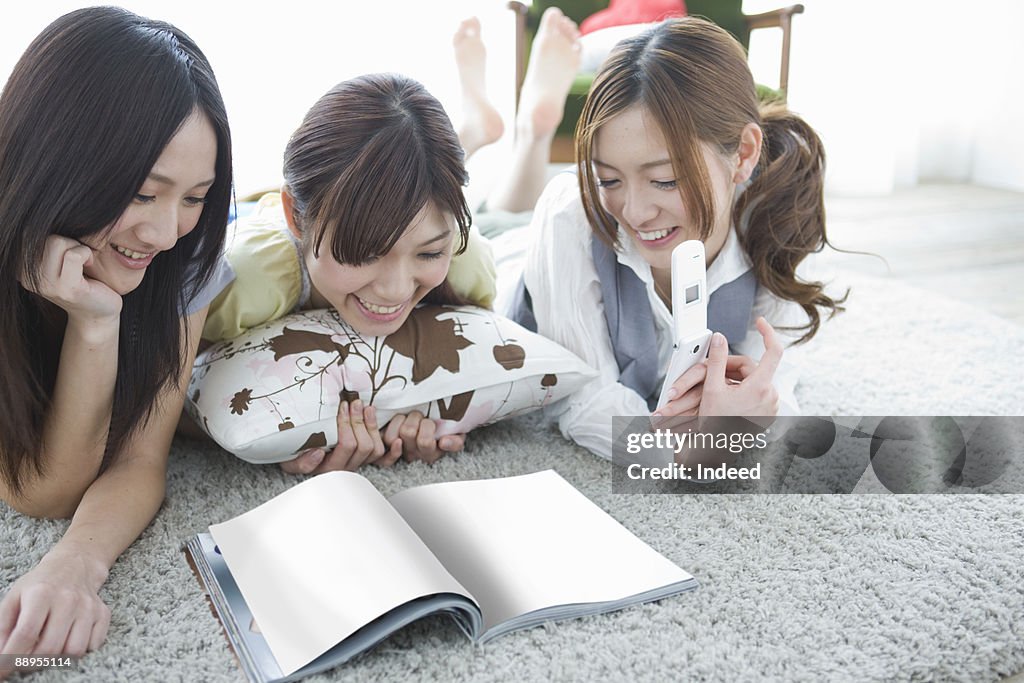 Three young women looking at magazine on floor
