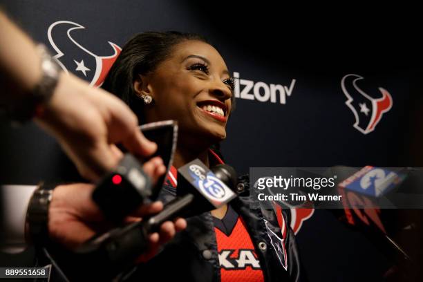 Simone Biles speaks with the media as she serves as an Honorary Texans Cheerleader before the game between the Houston Texans and the San Francisco...