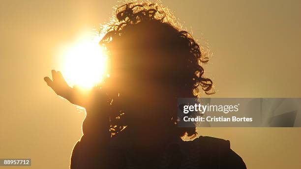 girl with curly hair holding the sun - bortes stockfoto's en -beelden