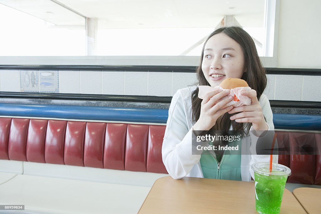 Teenage girl having burger and soda