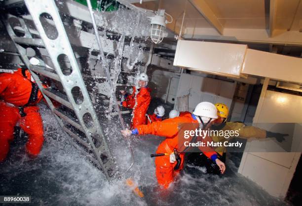 Royal Navy recruits try to stem the flow of flood water in a sinking ship simulator known as a Damage Repair Instructional Unit or HAVOC at the...