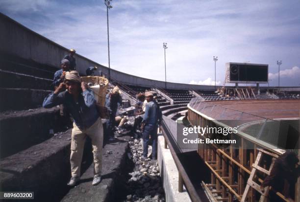Workmen carry baskets of construction rubble from grandstand area of the Velodrome, where cycling events will be held during the 1968 summer Olympics.