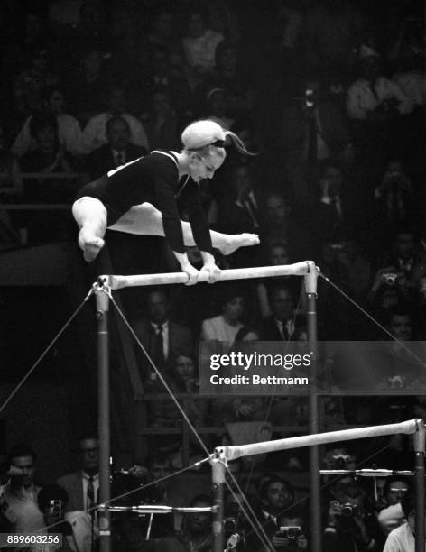 Vera Caslavska of Czechoslovakia performs on the asymmetrical bars to win a vote 9.90 points, of a possible perfect en, from the judges and a gold...