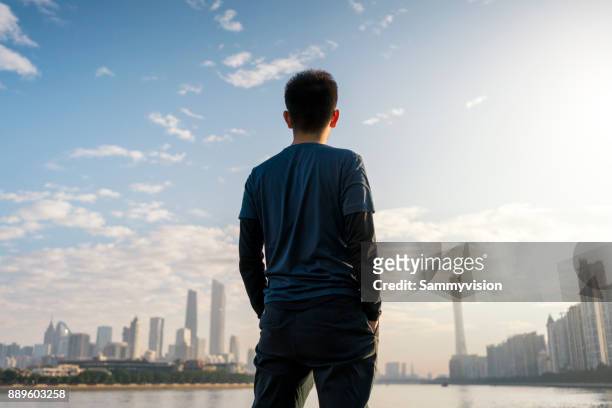 a man standing against the riverside. - human back stock pictures, royalty-free photos & images