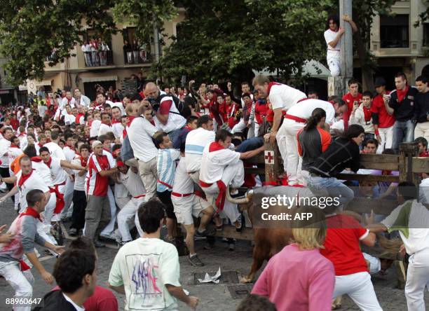 People run to cover behind a fence as a man is gored by a bull on July 10, 2009 in Pamplona, during the running of the bulls at the San Fermin...