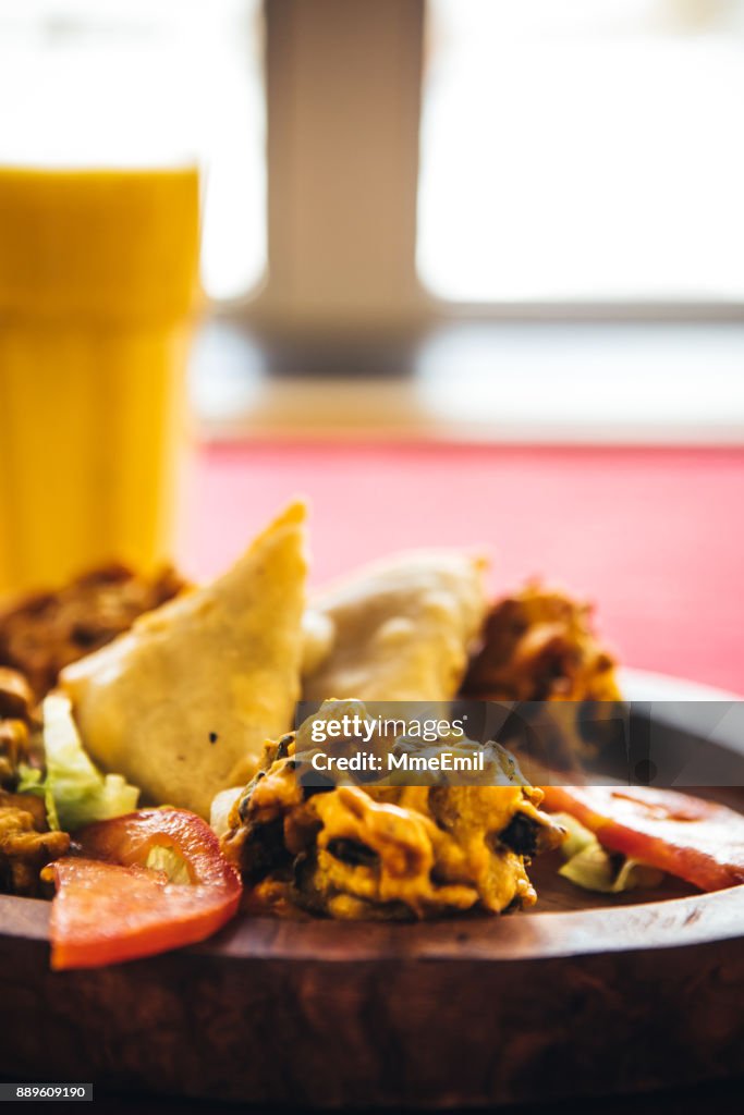 Pakora, bhaji and samosa on a wooden plate. North Indian food