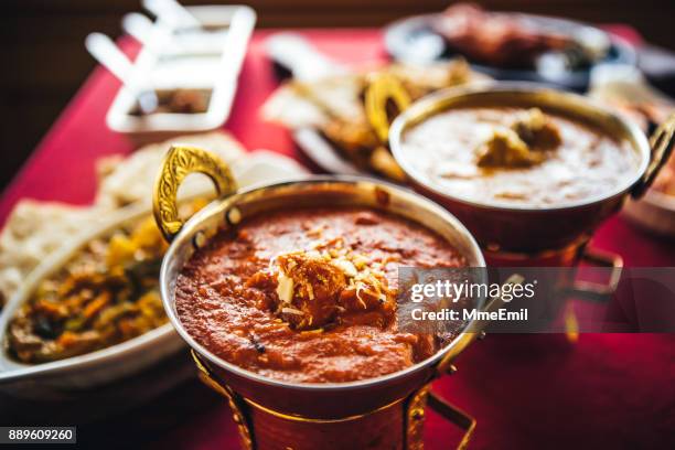 indian feast with butter chicken, chicken tandoori, lamb curry, vegetable curry, samosas, pakoras, bhajis, naan bread and basmati rice on a table. north indian food - banquet stock pictures, royalty-free photos & images