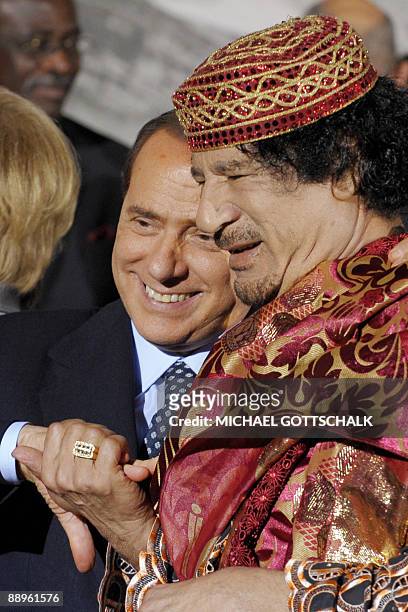 Italy's Prime Minister Silvio Berlusconi shakes hands with Libyan Leader Moamer Kadhafi during the Group of Eight summit in L'Aquila, central Italy,...
