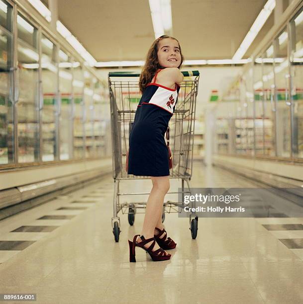 girl (5-7) pushing shopping cart, wearing high heeled shoes - child high heels stock pictures, royalty-free photos & images