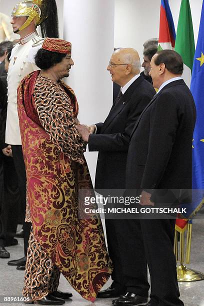 Italian President Giorgio Napolitano shakes hands with Libyan Leader Moamer Kadhafi under the eyes of Italy's Prime Minister Silvio Berlusconi during...