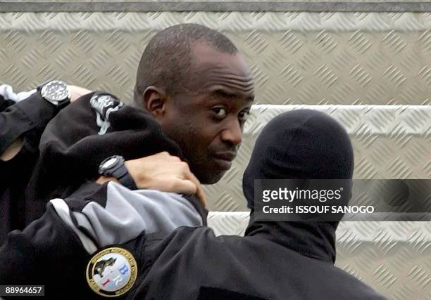 This picture taken on March 4, 2005 at Abidjan airport shows French alleged gang leader Youssouf Fofana escorted handcuffed by two plainclothes...