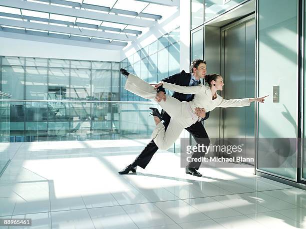 two officemates dancing to open the elevator door - aufzug business stock-fotos und bilder