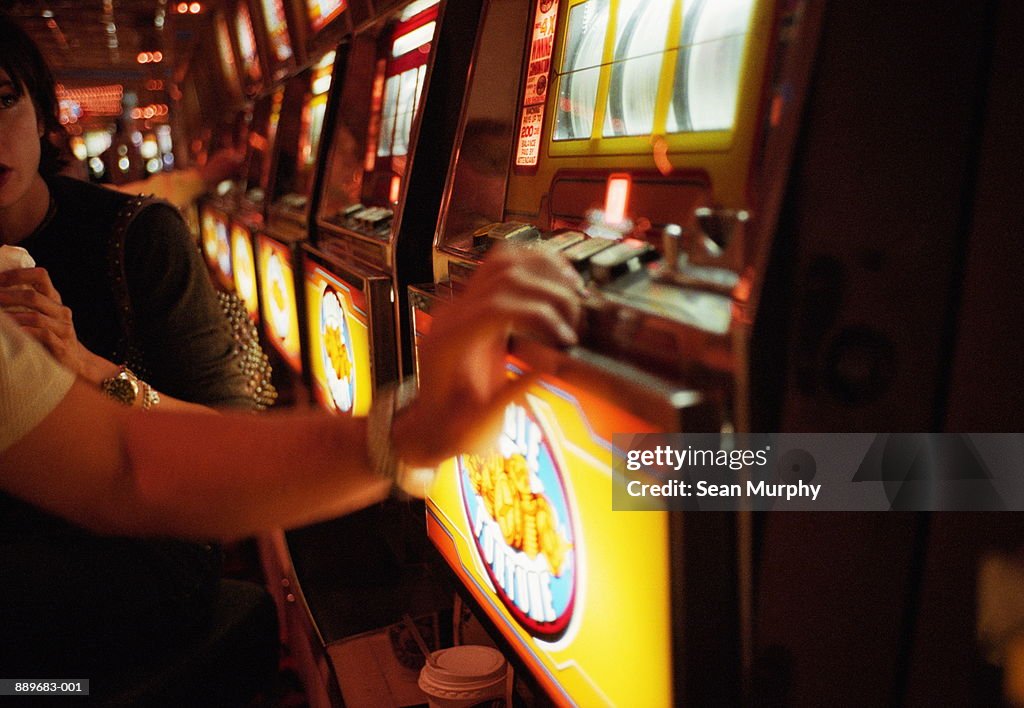 Couple playing slot machine in casino, Las Vegas, Nevada, USA