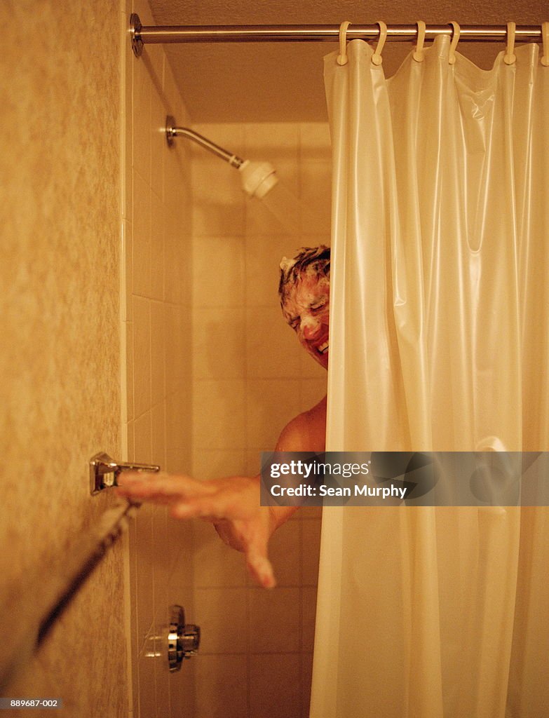 Man with soap over face reaching for empty towel rack