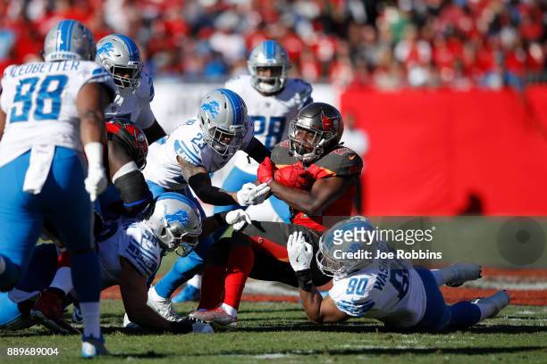 Darius Slay and Cornelius Washington of the Detroit Lions tackle Peyton Barber of the Tampa Bay Buccaneers in the third quarter of a game at Raymond...