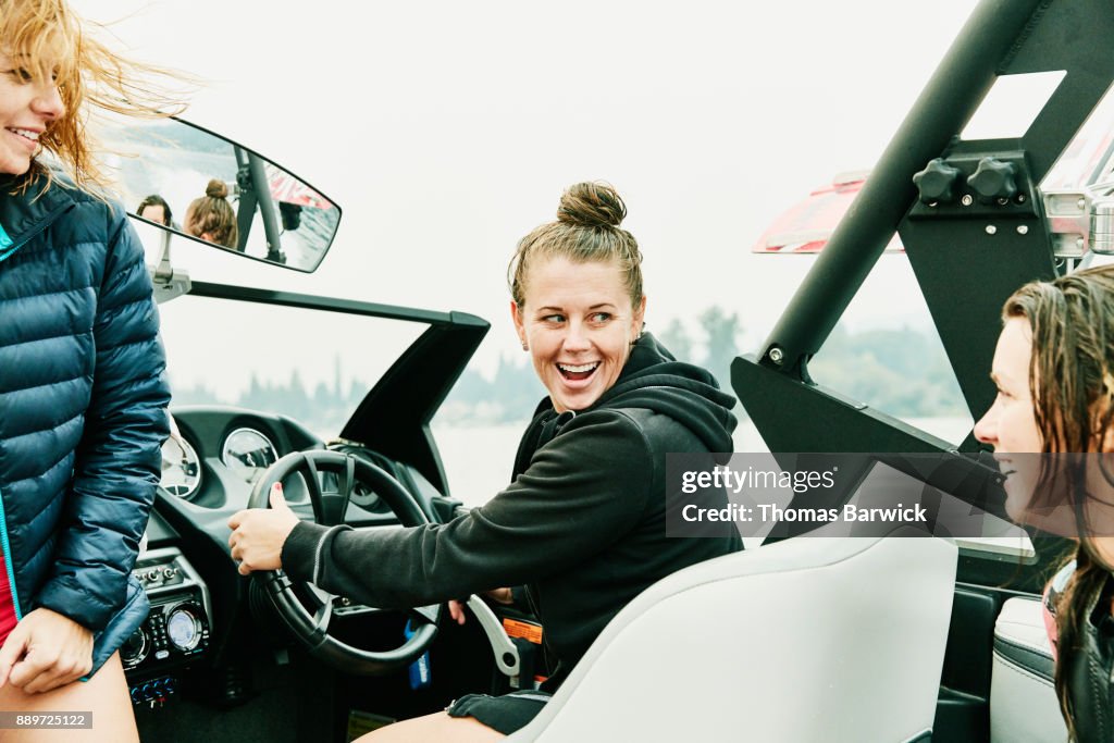 Smiling female friends riding in boat during early morning wakeboarding session on lake