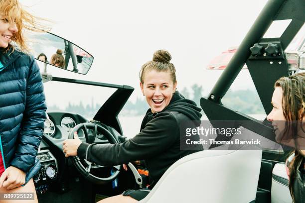 smiling female friends riding in boat during early morning wakeboarding session on lake - only mid adult women stock pictures, royalty-free photos & images