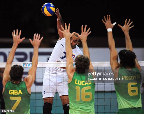 Venezuelan Luis Diaz spikes the ball over Brazilian Giba , Lucas and Vissotto during their Volleyball World League match in Caracas on July 10, 2009....