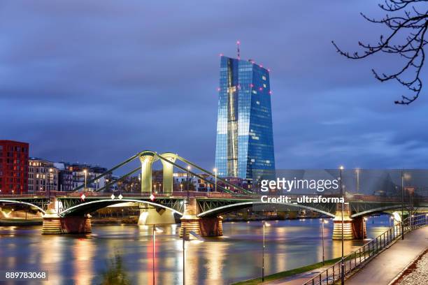 view of the illuminated frankfurt am main skyline with flossen brucke and european central bank at dusk - hesse germany stock pictures, royalty-free photos & images