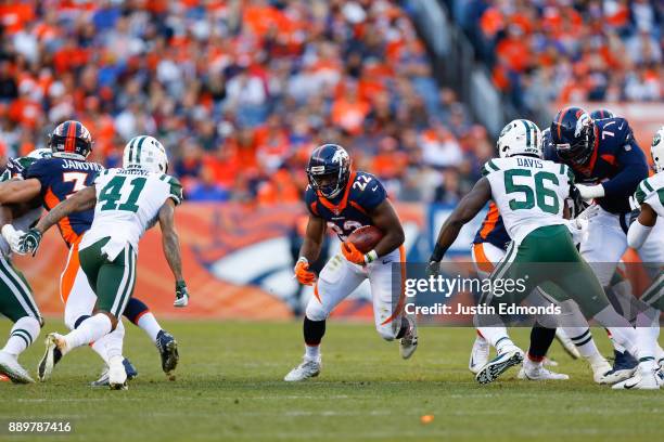 Running back C.J. Anderson of the Denver Broncos runs through a hole before being tackled by cornerback Buster Skrine of the New York Jets and...