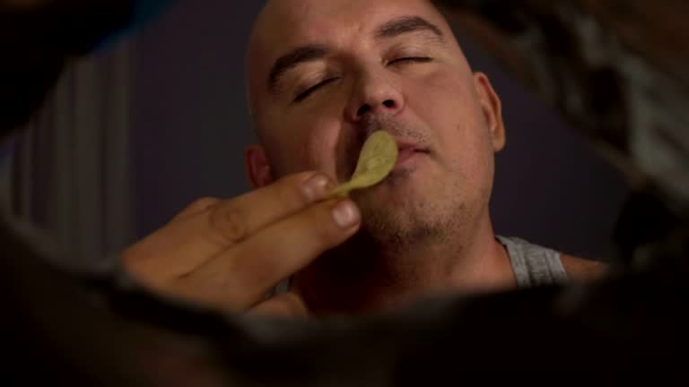 Chippy Overload Overweight man chewing salty potato chips, overeating junk food, view ...