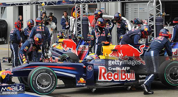 Red Bull's Australian driver Mark Webber and his German team mate Sebastian Vettel stand in their cars in the pits of the Nurburgring racetrack on...