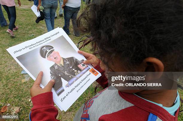 Child watches a leaflet depicting de facto President Roberto Micheletti as a nazi officer, as supporters of toppled Honduran President Manuel Zelaya...