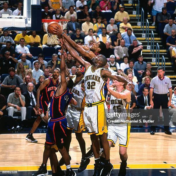 Marcus Camby of the New York Knicks grabs a rebound from a crowd including Dale Davis of the Indiana Pacers in Game Five of the Eastern Conference...