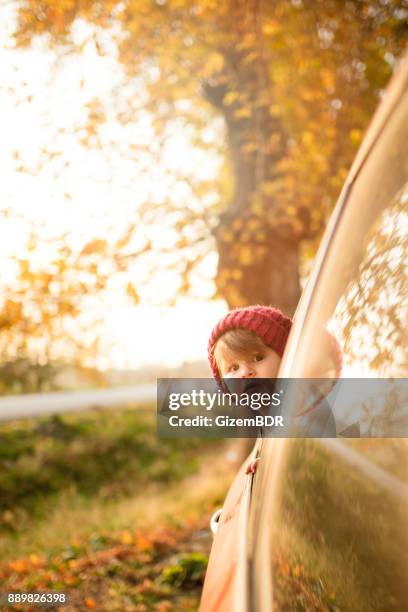 de kleine jongen kijkt uit het raam van de auto - sun flare on glass stockfoto's en -beelden