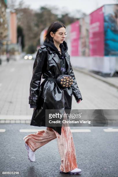 Maria Barteczko wearing black shiny vinyl trench coat Asos, black hoody MUF10, nude velvet wide leg trousers Alice+Olivia, purple Air Max sneaker...