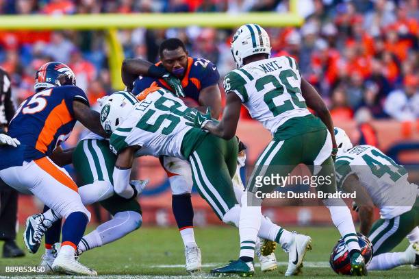Running back C.J. Anderson of the Denver Broncos loses his helmet as he is hit by inside linebacker Darron Lee of the New York Jets during a game at...