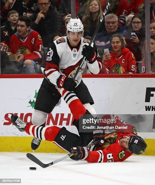 Jordan Oesterle of the Chicago Blackhawks hits the ice after being tripped by Dylan Strome of the Arizona Coyotes at the United Center on December...