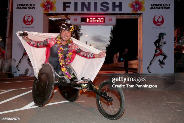 Wheelchair participant Masazumi Soejima poses with a flag flag after crossing the finish line to win the Men's Wheelchair division during the...