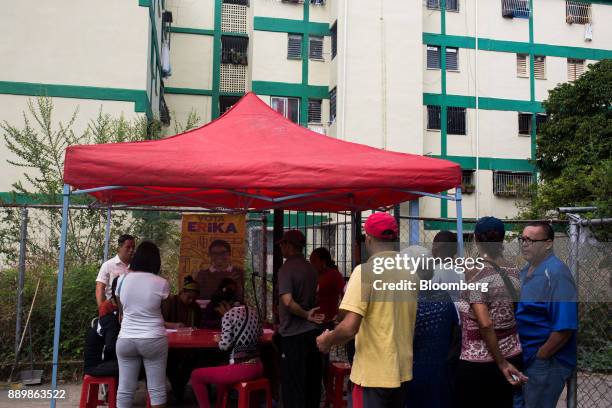 Voters wait in line outside a polling station to use government issued "Carnet de La Patria" electronic identity cards to register to vote during a...