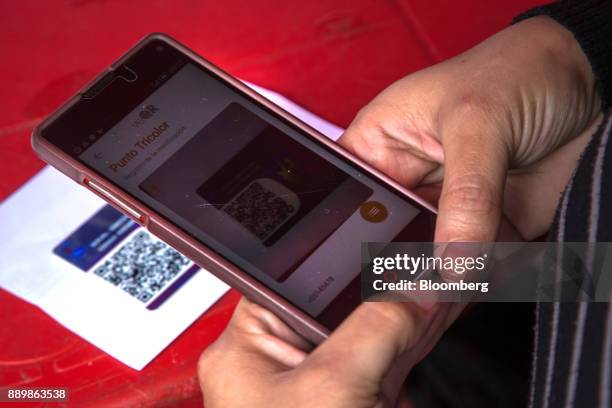 An electoral official scans a Quick Response code on a government issued "Carnet de La Patria," electronic identity card, at a checkpoint outside a...