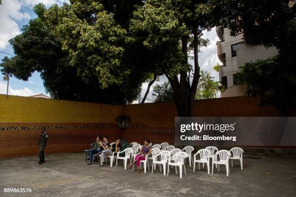 Voters wait as a member of the military stands guard outside a polling station during a nationwide mayoral election in Caracas, Venezuela, on Sunday,...