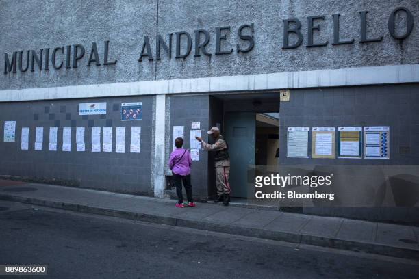Member of the Bolivarian Militia speaks with a voter outside a polling station during a nationwide mayoral election in Caracas, Venezuela, on Sunday,...