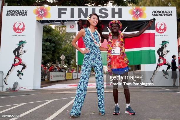 Dennis Kimetto of Kenya poses with Miss Hawaii USA 2018 Julianne Chu after winning the men's marathon during the Honolulu Marathon 2017 on December...