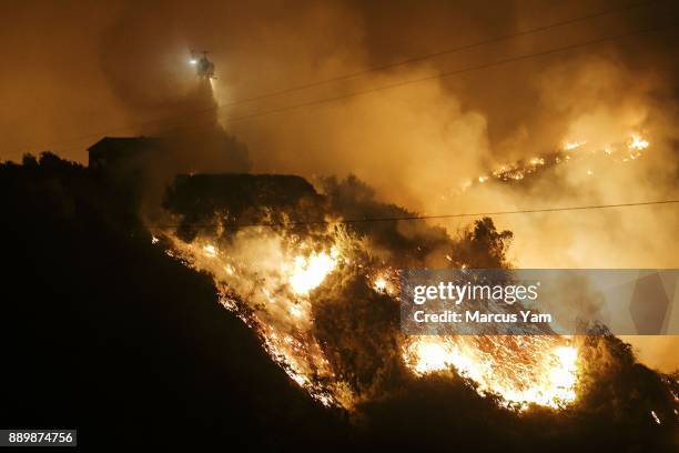 Helicopter makes a water drop as flames make its way up the Shepard Mesa neighborhood, as the Thomas Fire raged out of control overnight, in...