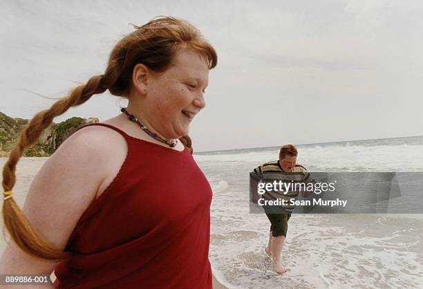 two children (11-13) running on beach - young chubby girl photos et images de collection