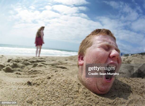 boy (10-12) buried in sand, girl walking away - girl 10 12 stock pictures, royalty-free photos & images