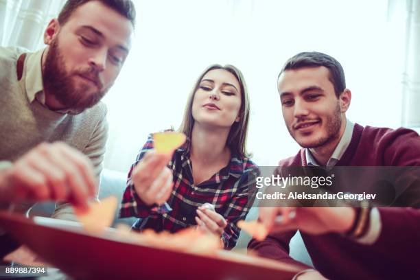group of friend eating snacks, conversing and having fun time together - college dorm party stock pictures, royalty-free photos & images